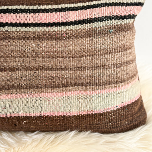 Woven Moroccan pillow with brown, pink, and black stripes on a white background