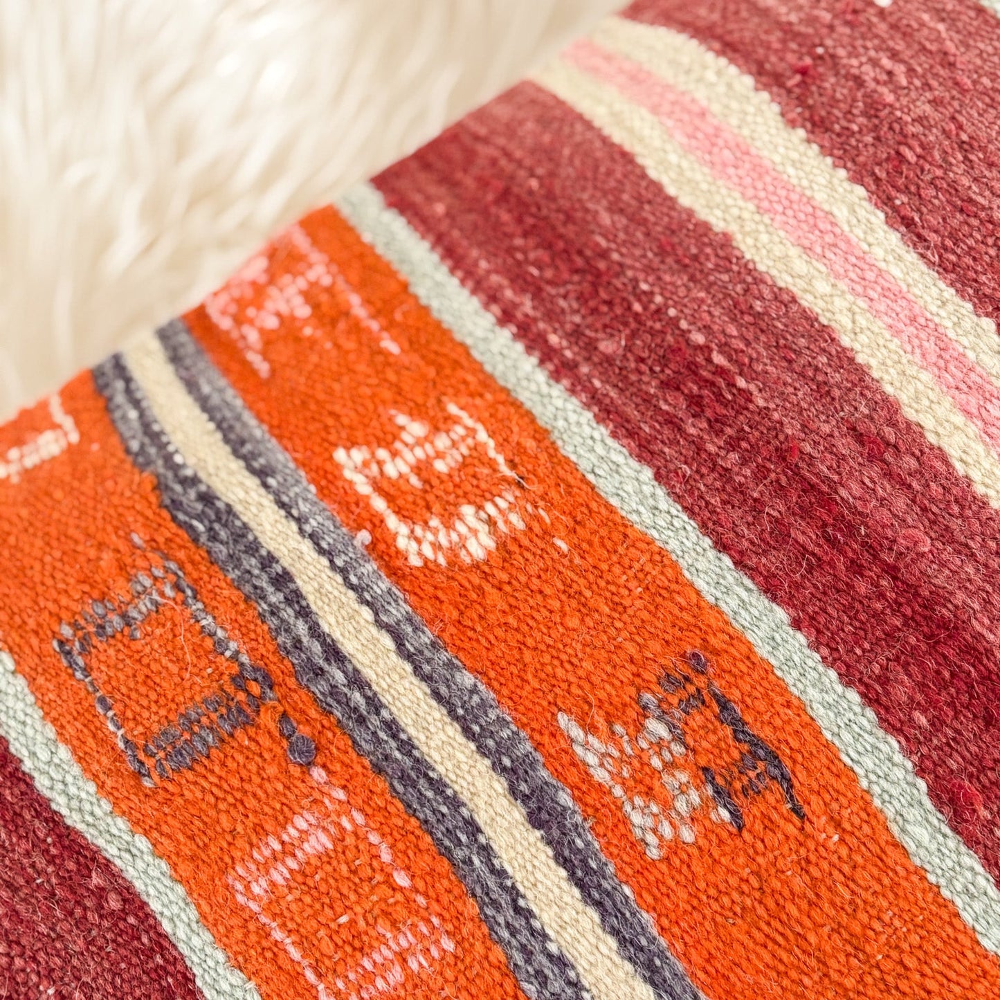 Close-up of a textured fabric with red, orange, and beige stripes.