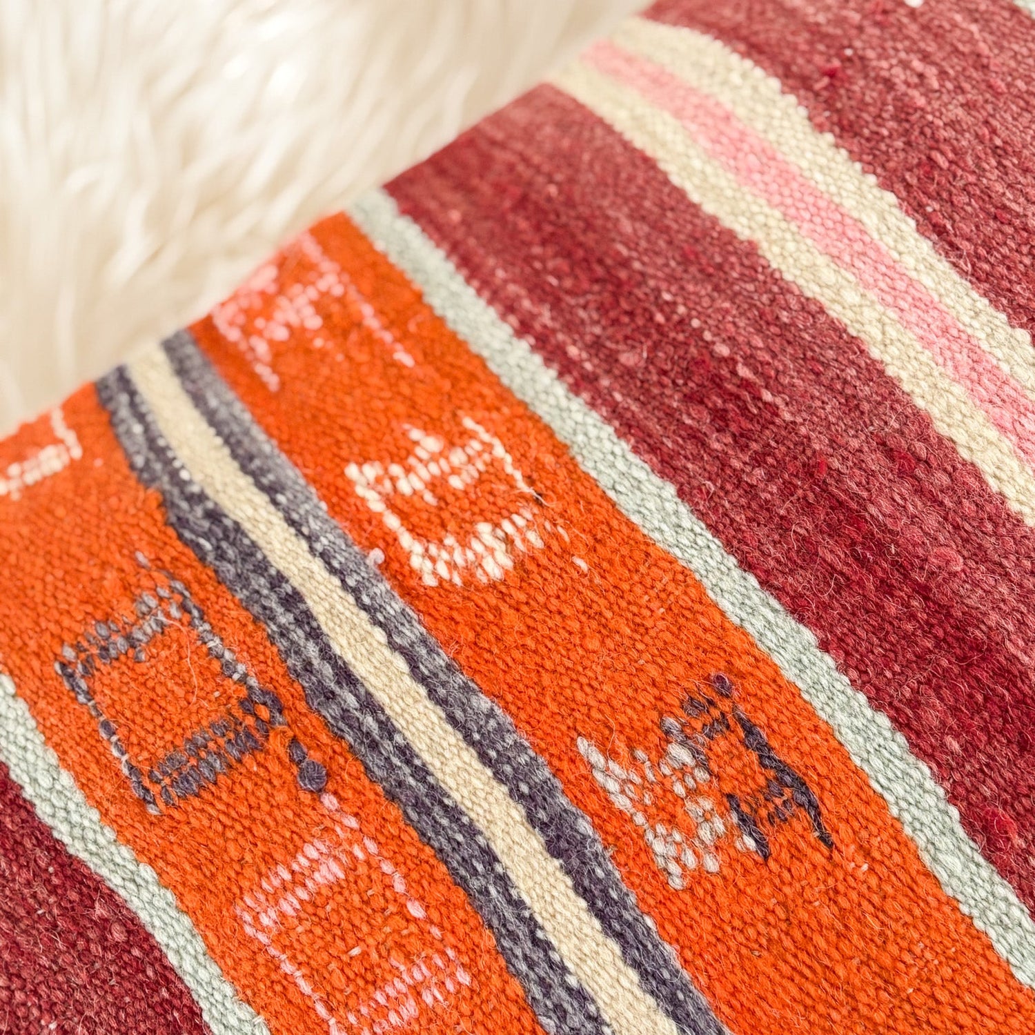 Close-up of a textured fabric with red, orange, and beige stripes.